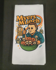 Towel with 'Myers Munch' design featuring a character holding pumpkins and a mask on a dark background.